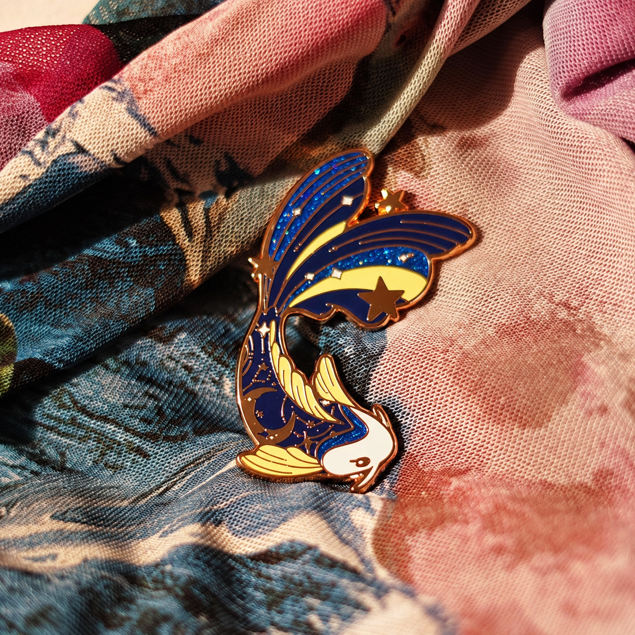 Navy and gold koi enamel pin with stars; enhanced photograph of the finished product